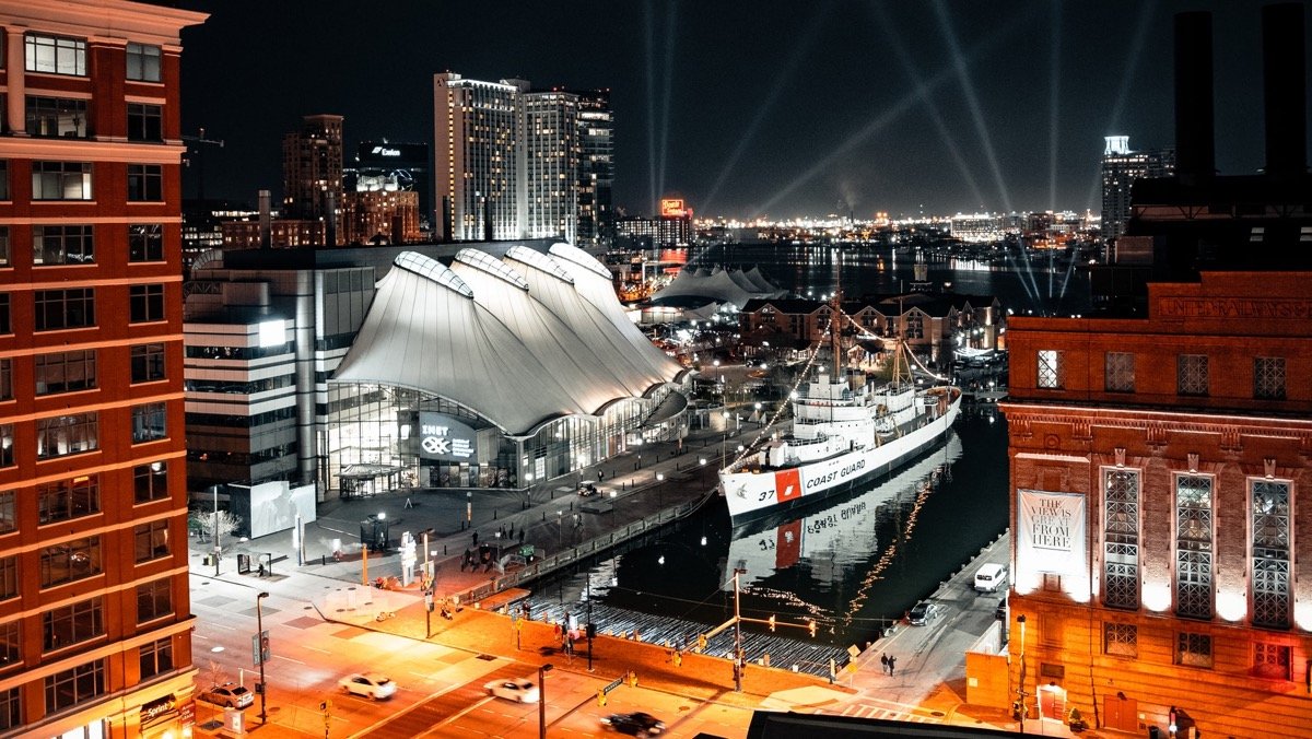 Night scene of the Columbus Center's glowing, sail-like roof and the USCG Cutter 37 at dock.