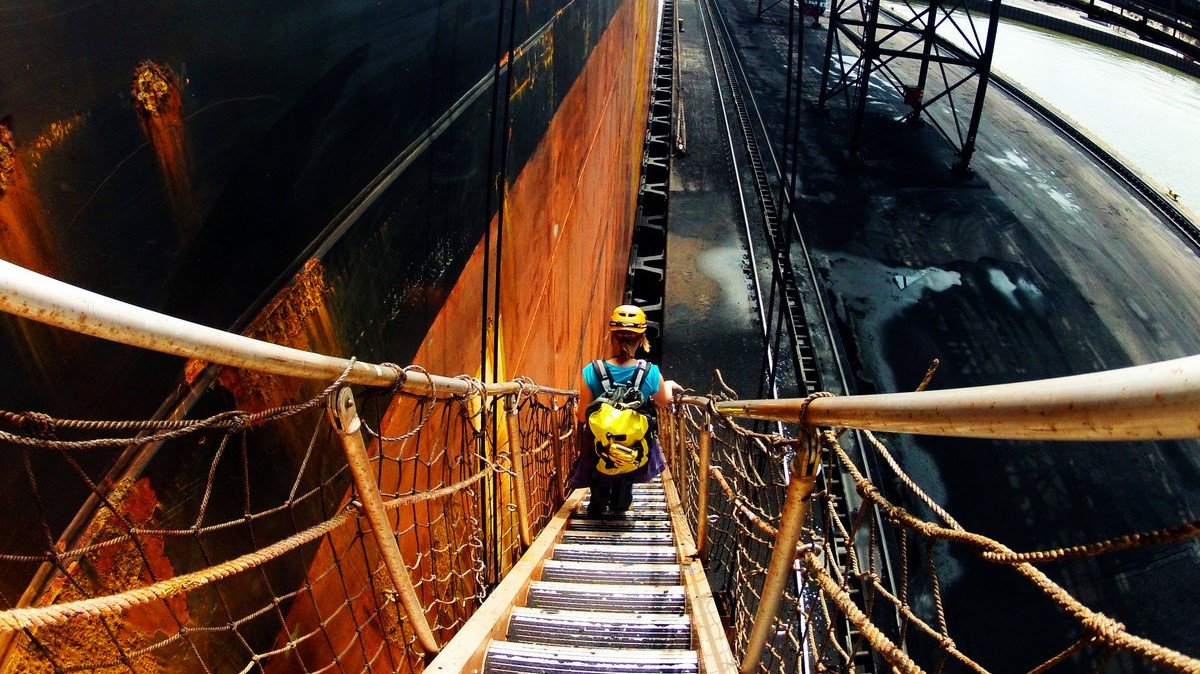 Scientist descends a gangway between a large ship and a port