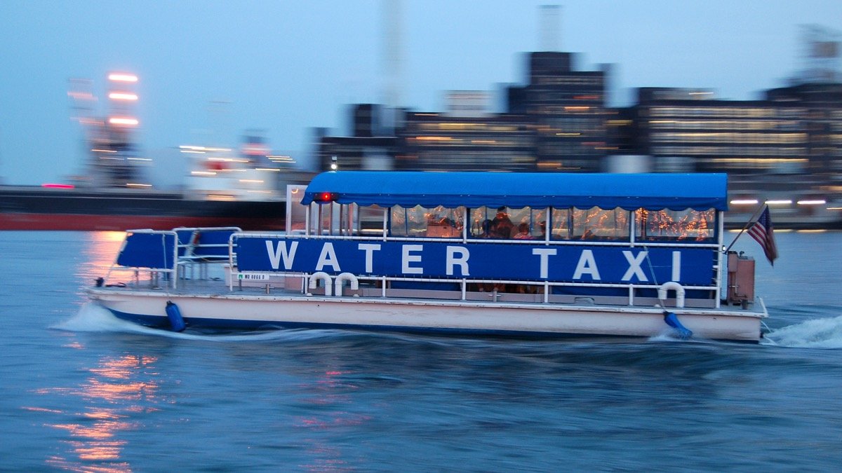 A water taxi speeds by Fells Point at sunset.